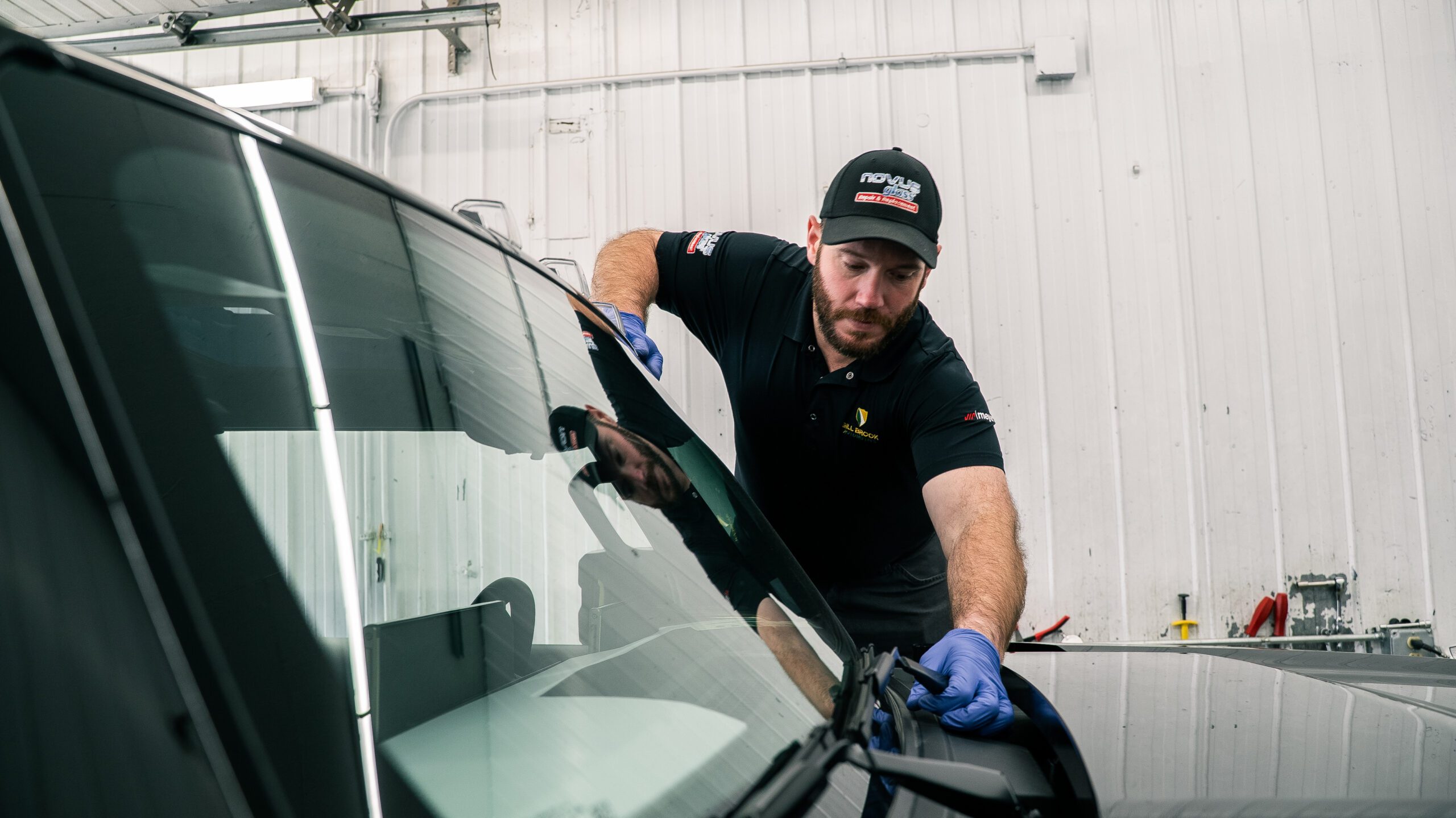 Man repairing a vehicle windshield on a black vehicle